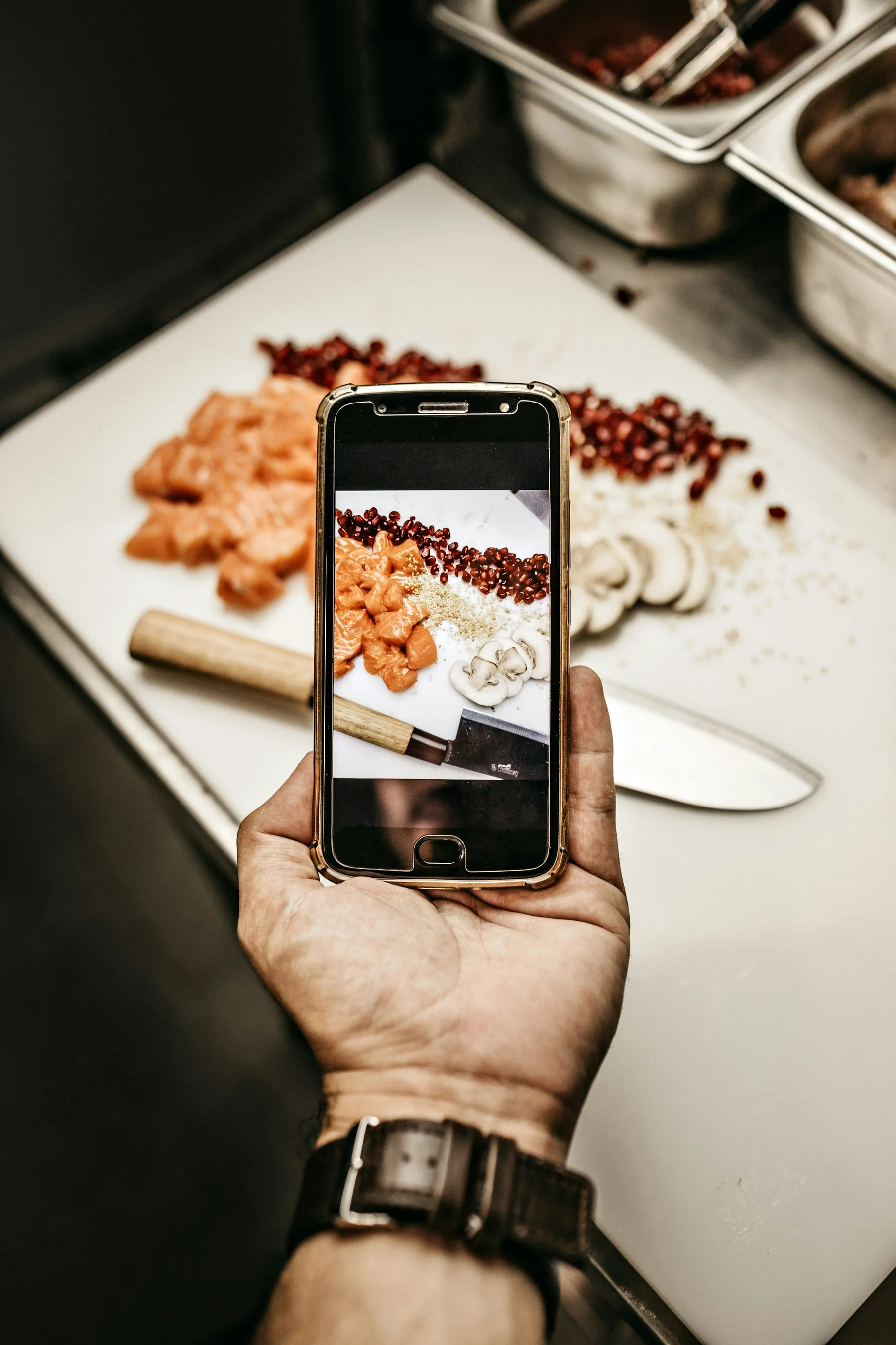 A person using a phone to photograph food during preparation