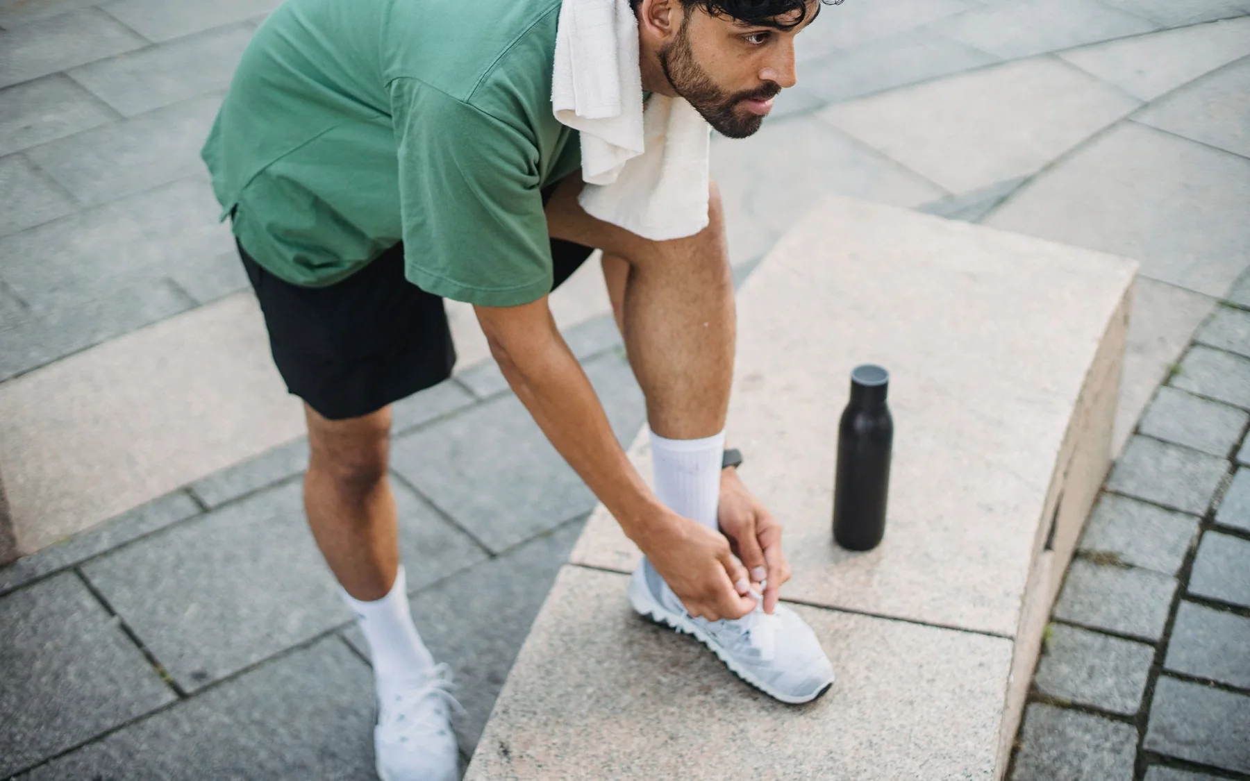 A runner tying his shoes before an outdoor workout
